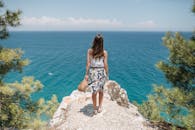 穿着花裙的女人站在悬崖边，欣赏宁静的海景