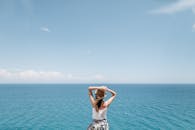 一个戴着夏季帽子的女人在阳光明媚的日子里欣赏着令人叹为观止的海景