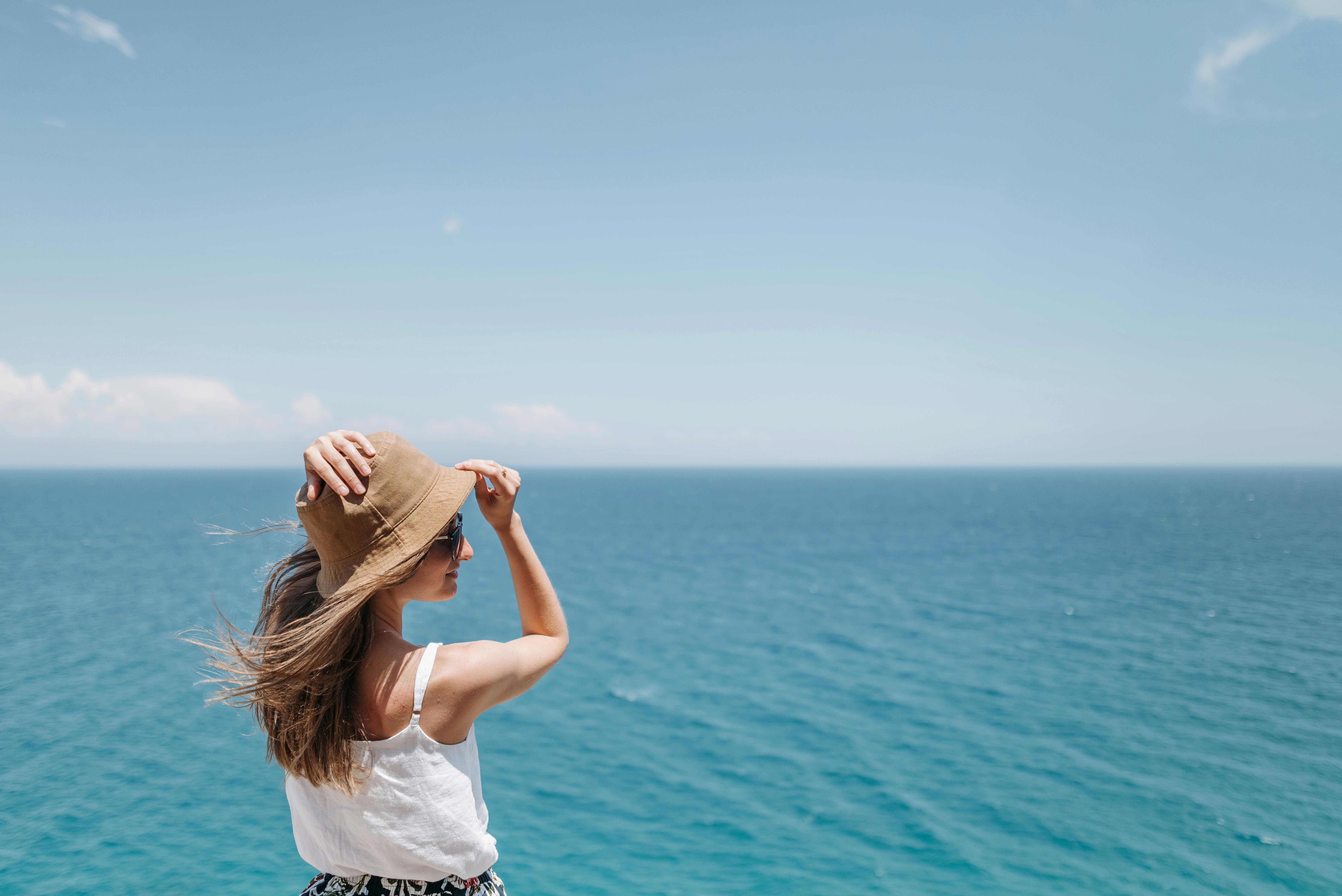 戴着草帽和太阳镜的女人在海边享受阳光明媚的一天