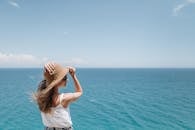 戴着草帽和太阳镜的女人在海边享受阳光明媚的一天