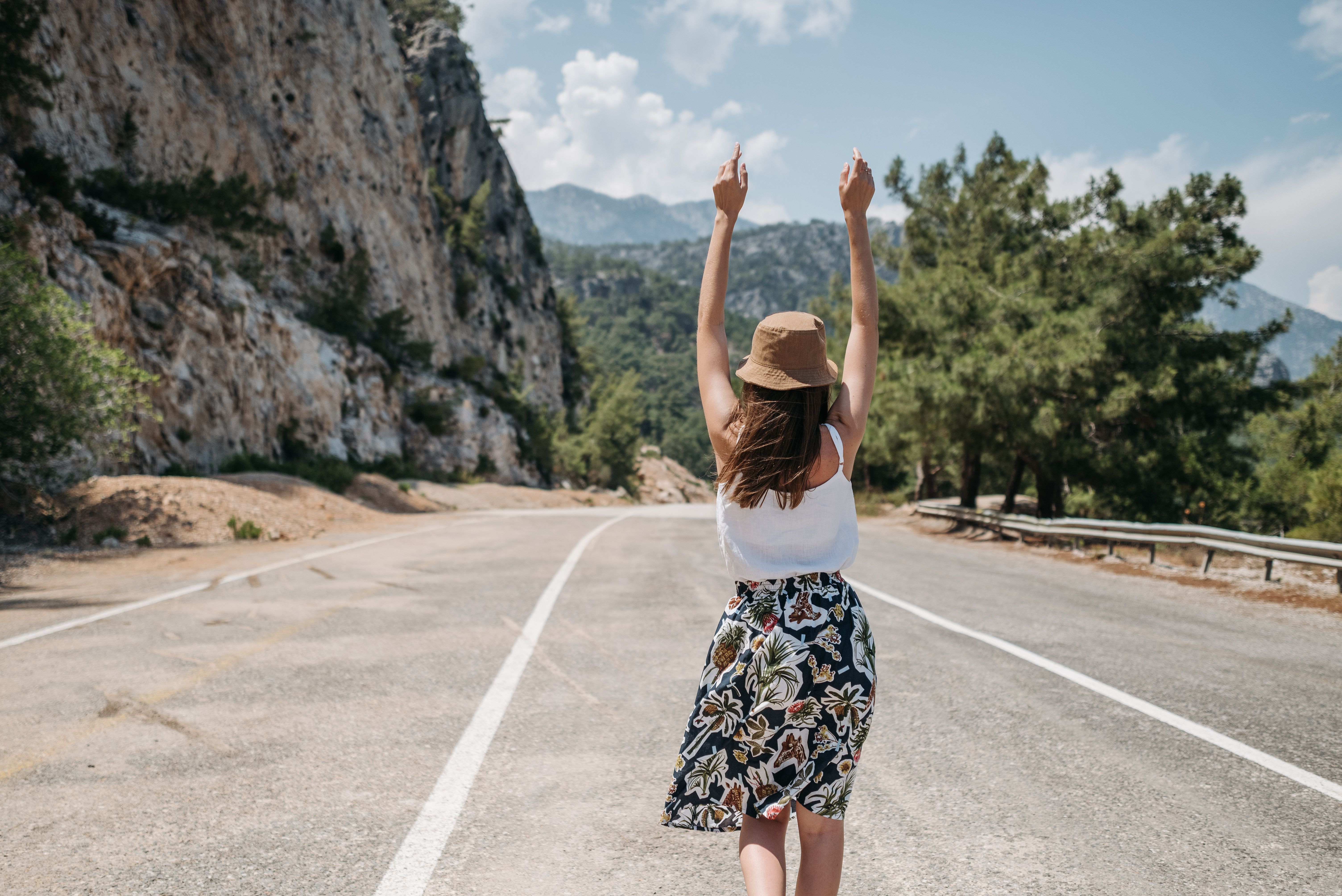 당일치기 근교 여행지 추천 관련 이미지 &mdash; A woman with arms raised stands joyfully on a mountain road in summer.