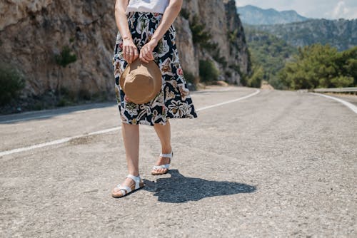 Woman in White Sandals Walking on Asphalt Road
