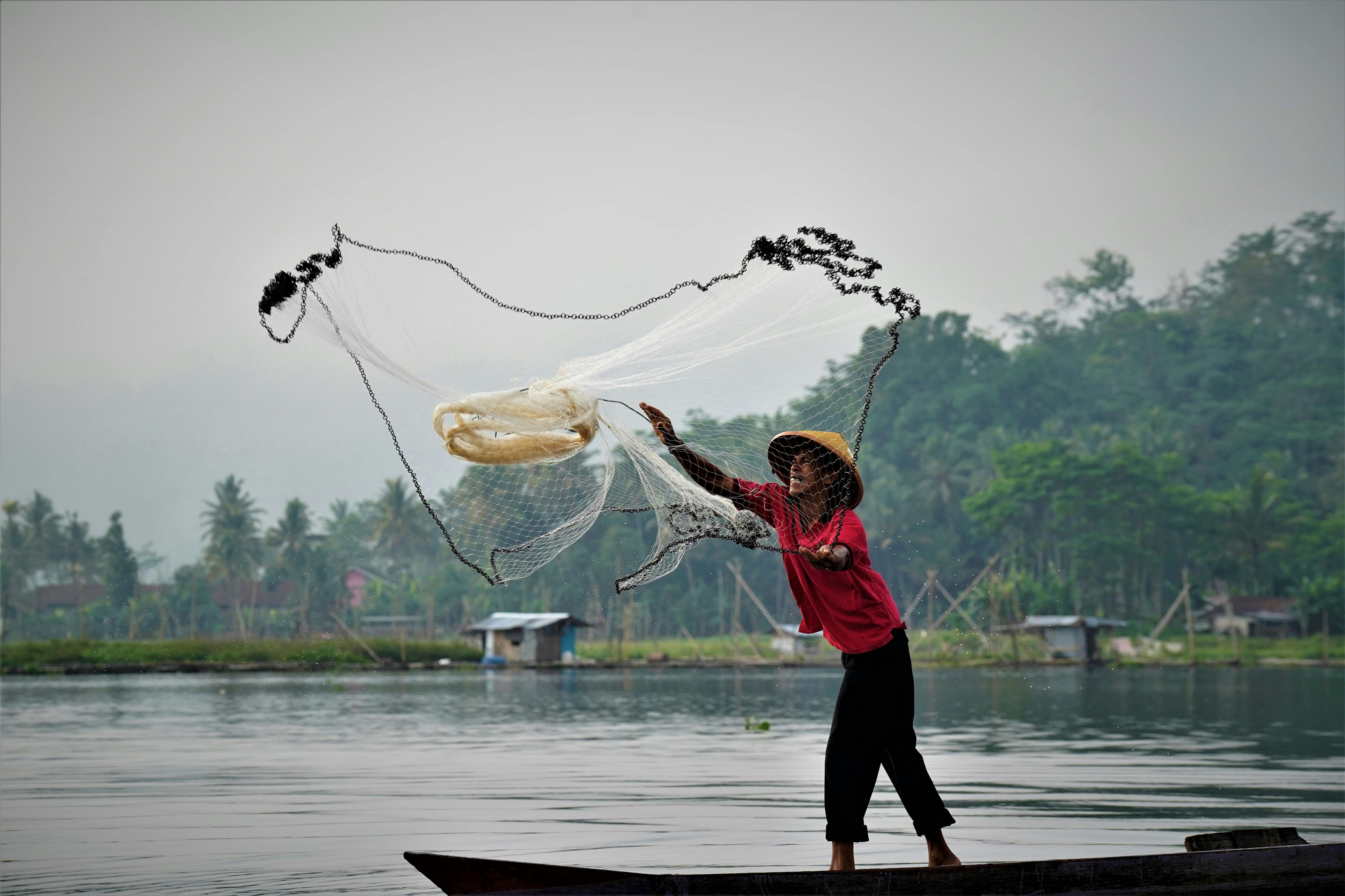 Man Throwing a Fishing Net on Water · Free Stock Photo