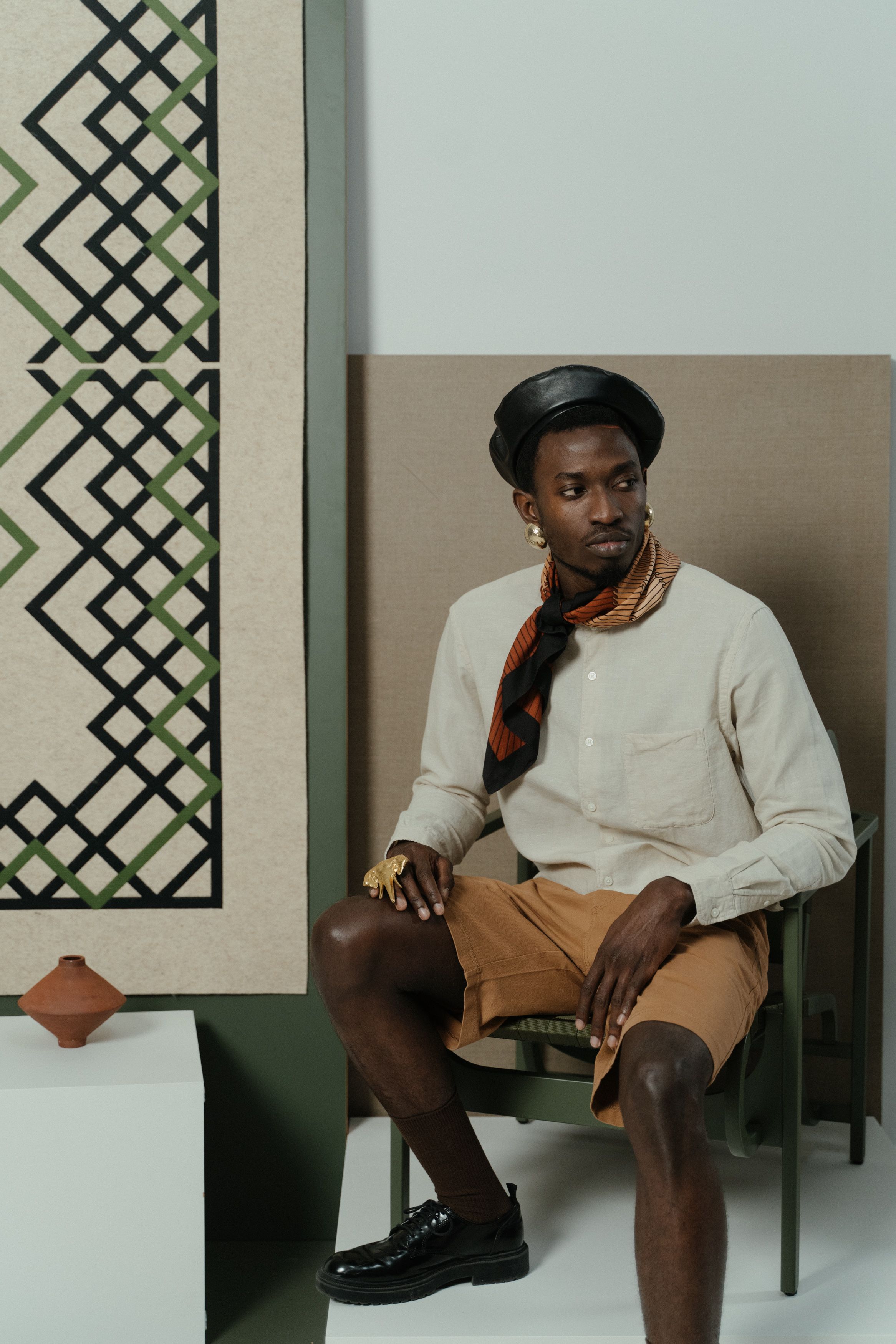 Young stylish man seated indoors at an art museum, exuding modern fashion.
