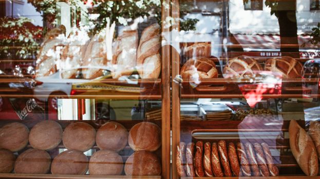 Freshly baked artisanal breads displayed in a bakery window showcasing a variety of loaves.