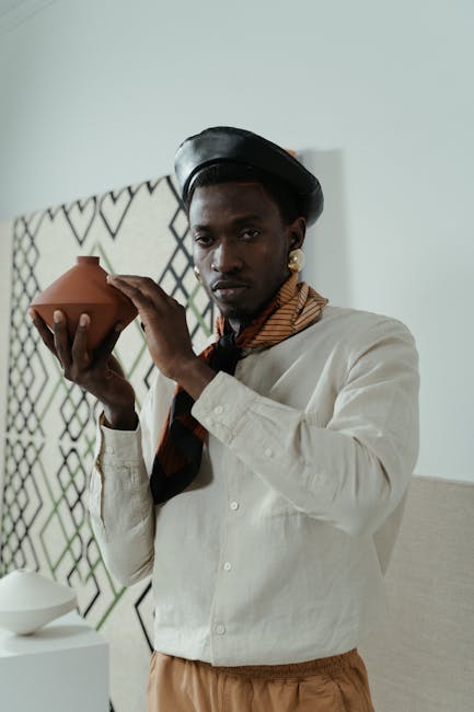 A fashionable man in an art gallery holding a ceramic pot, showcasing elegance and style.