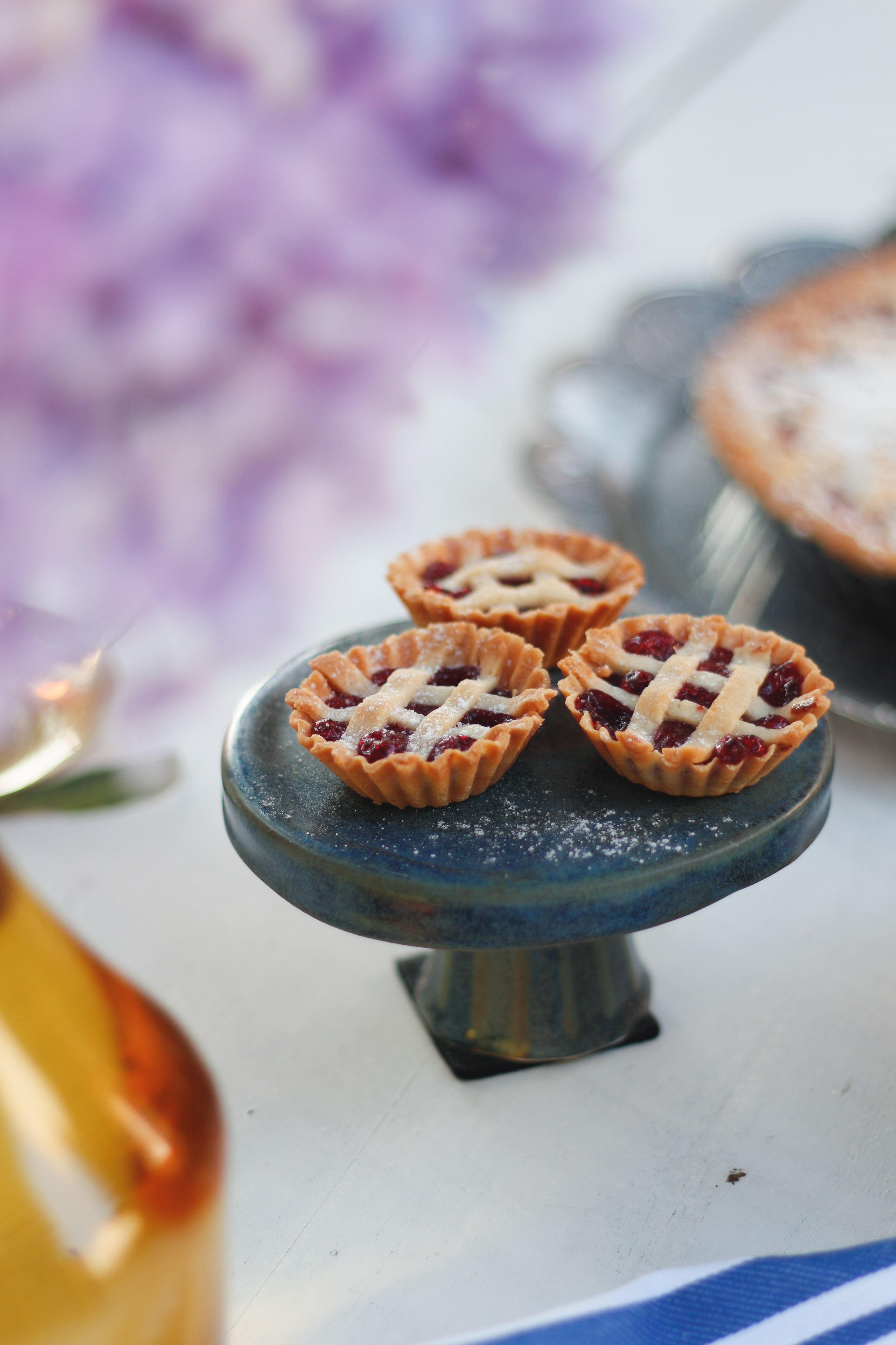 Three mini berry pies on a pedestal, styled with elegant food design.