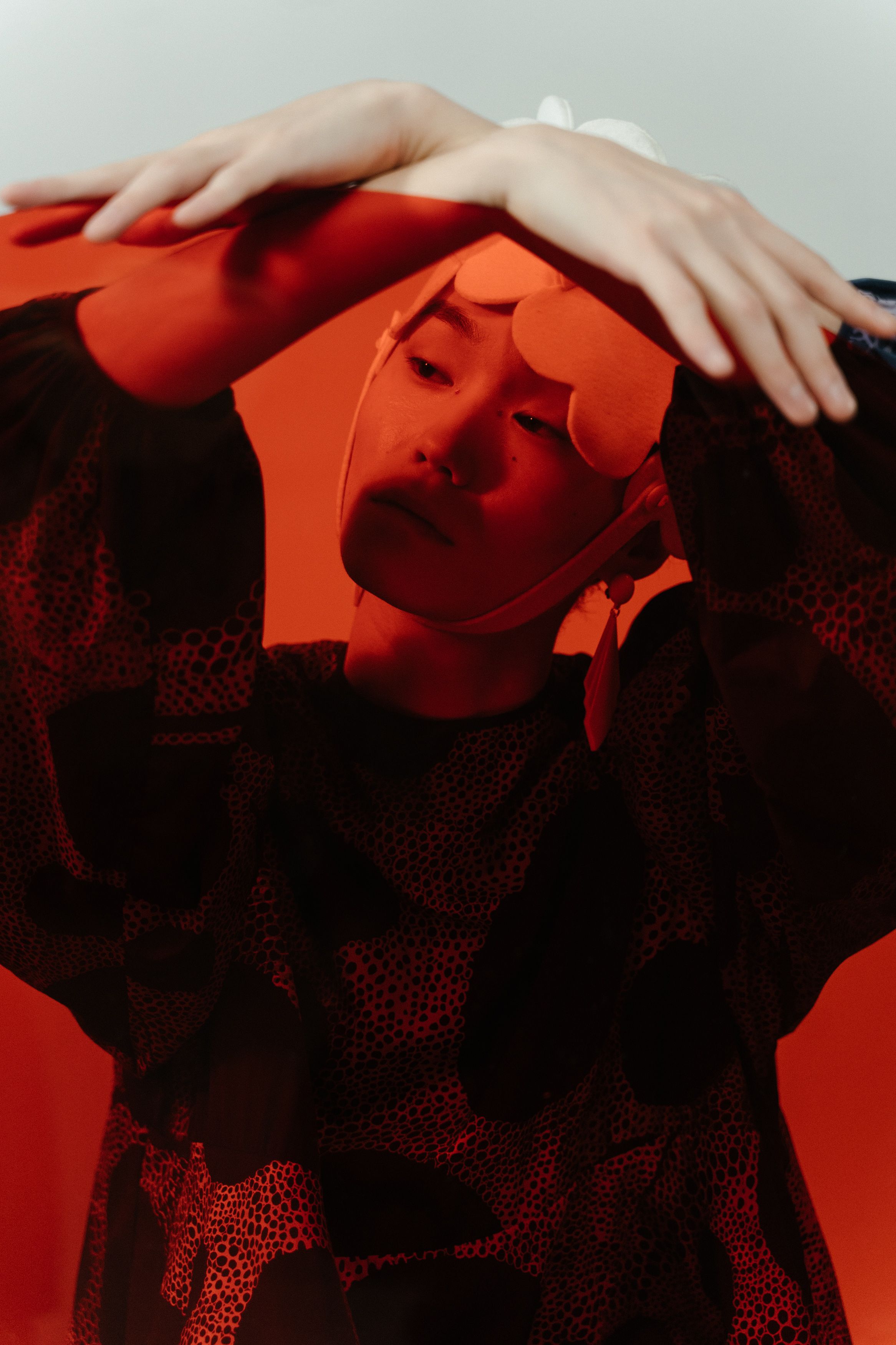 Stylized portrait of a woman under artistic red lighting, posing elegantly.