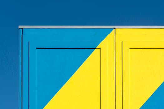 Abstract image of a building wall with striking blue and yellow geometric patterns against a clear sky.