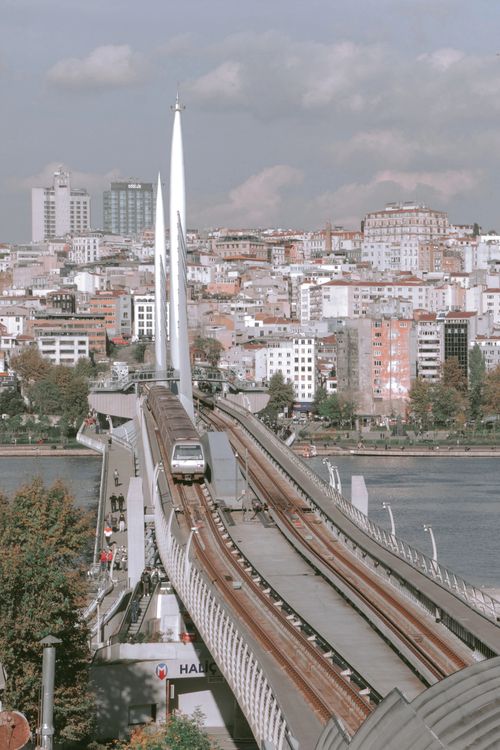 Free Contemporary rail transit crossing a bridge with a sprawling urban cityscape in the background. Stock Photo
