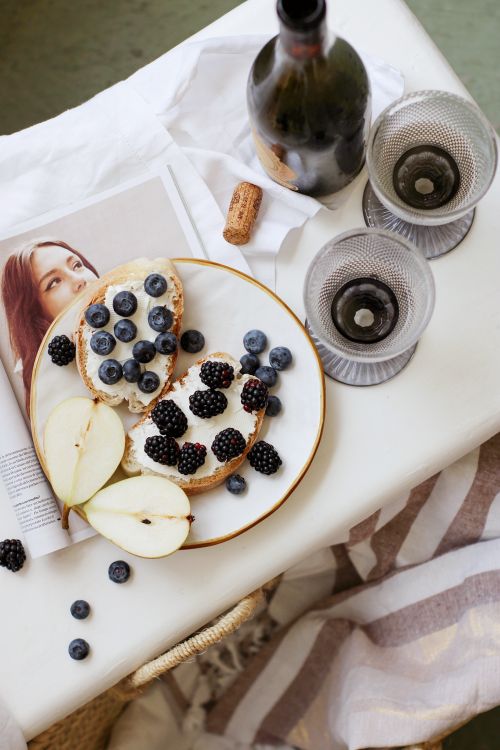 Free Flatlay of berry-topped toasts with pear slices and wine glasses, perfect for rustic dining. Stock Photo