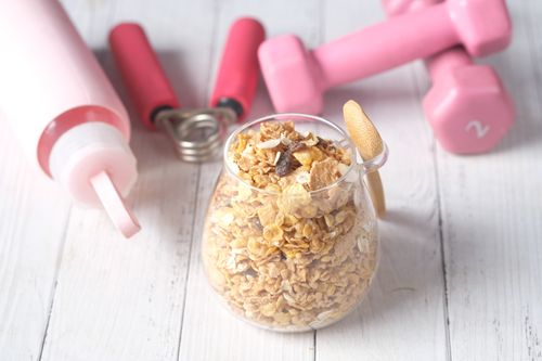 Free A glass jar of granola with pink dumbbells and a water bottle for a fitness-inspired healthy meal. Stock Photo
