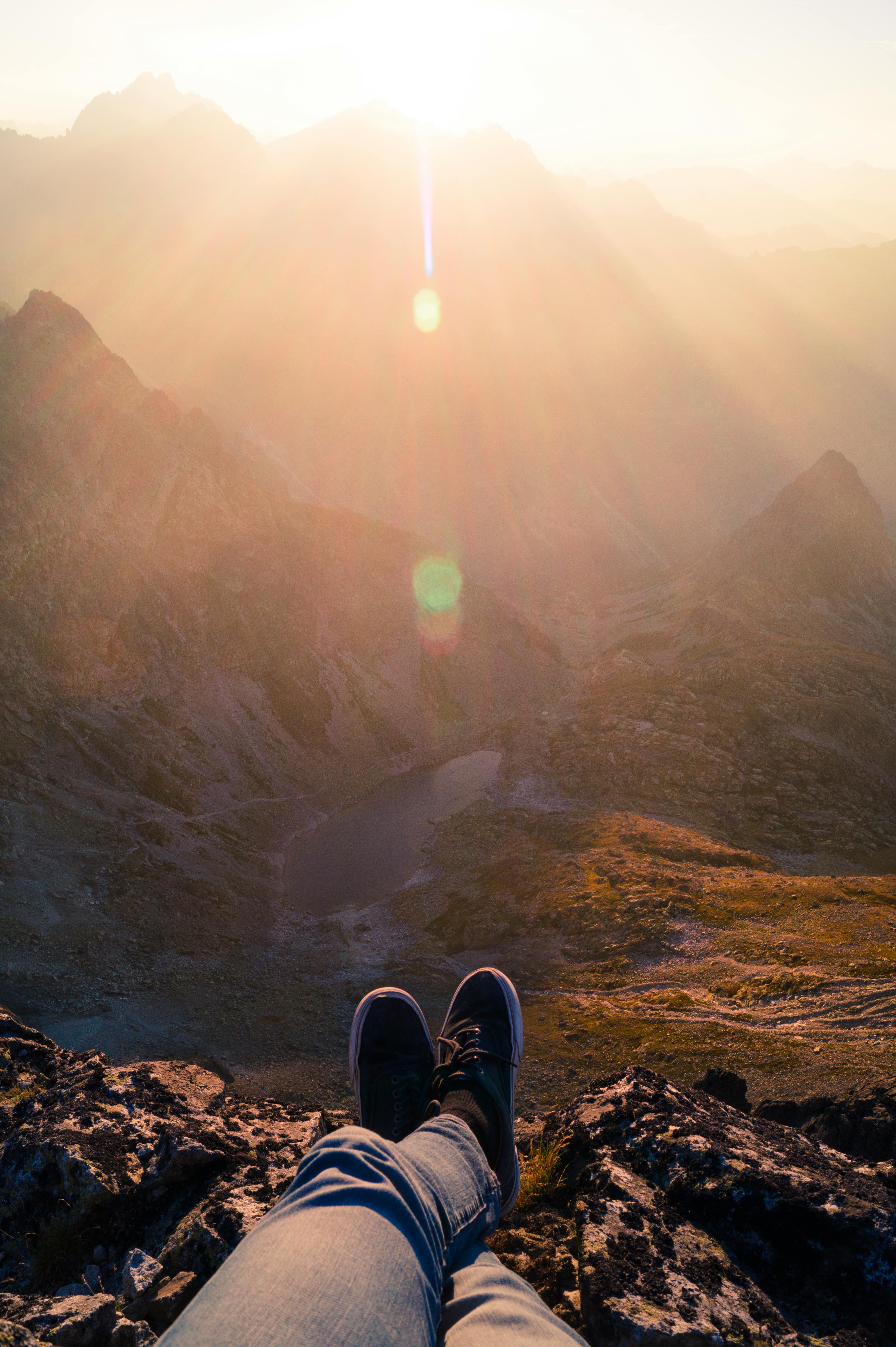 person wearing black sneakers sitting in mountain