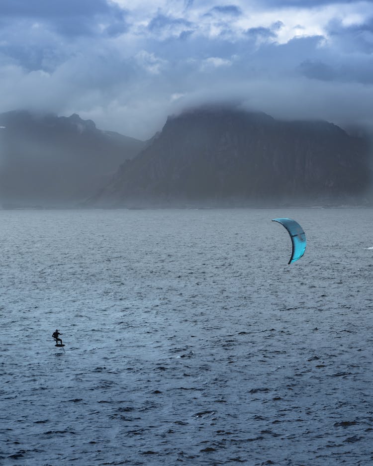 Person Kite Surfing On Sea Near Mountain