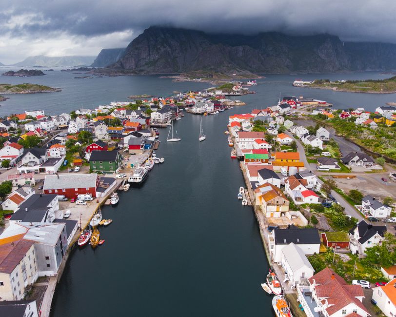 Unforgettable Helicopter Over Trolltunga and Waterfall Sightseeing from Bergen Review Review 2026 - A captivating aerial shot of a colorful Norwegian town with boats on a calm harbor, surrounded by striking mountains.