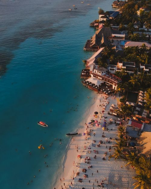 Free Stunning aerial shot of Nungwi Beach in Tanzania with people enjoying the shore at sunset. Stock Photo