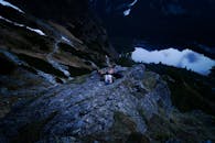 黄昏时分，一名孤独的徒步旅行者躺在岩石上，欣赏山间宁静的湖景