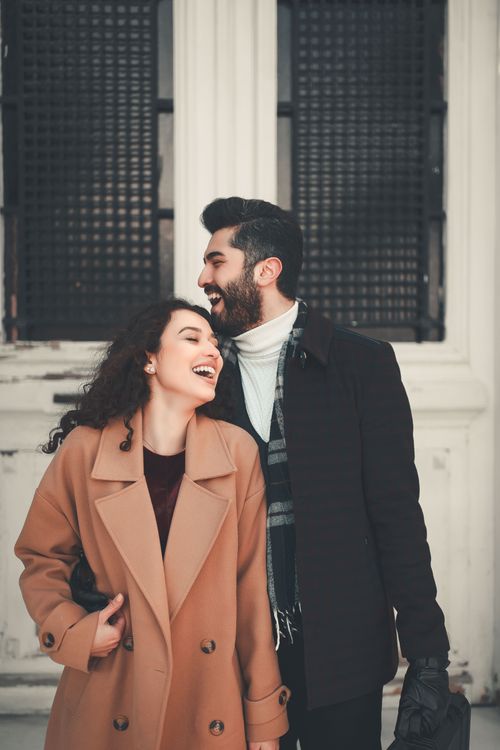 Free Charming couple in winter coats laughing together outdoors, showcasing joy. Stock Photo