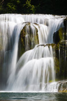Beautiful waterfall flowing over rocks, showcasing nature's tranquility and motion in a serene landscape.