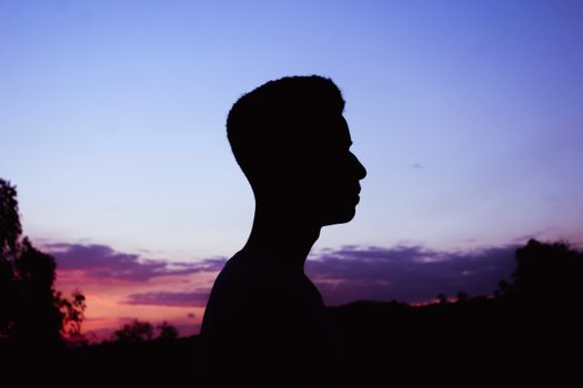 A striking silhouette of a man against a vibrant dusk sky, evoking a peaceful mood.