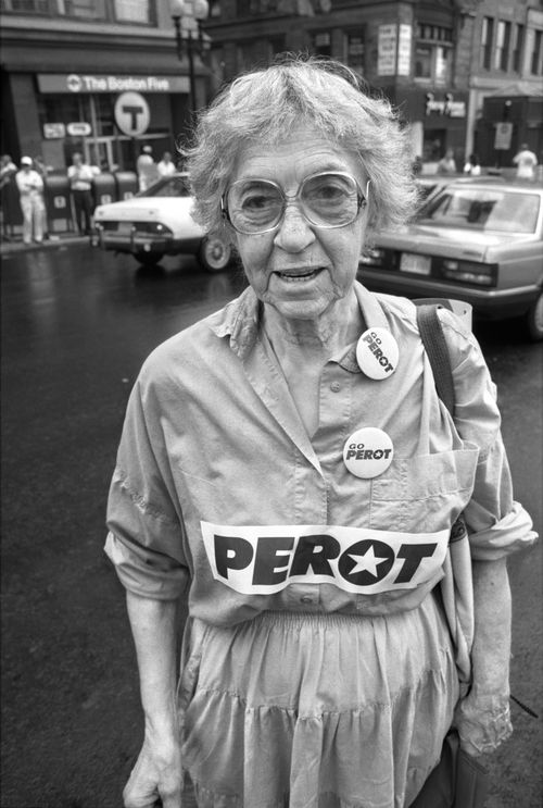 Free Black and white photo of an elderly woman wearing Perot campaign pins on a city street. Stock Photo