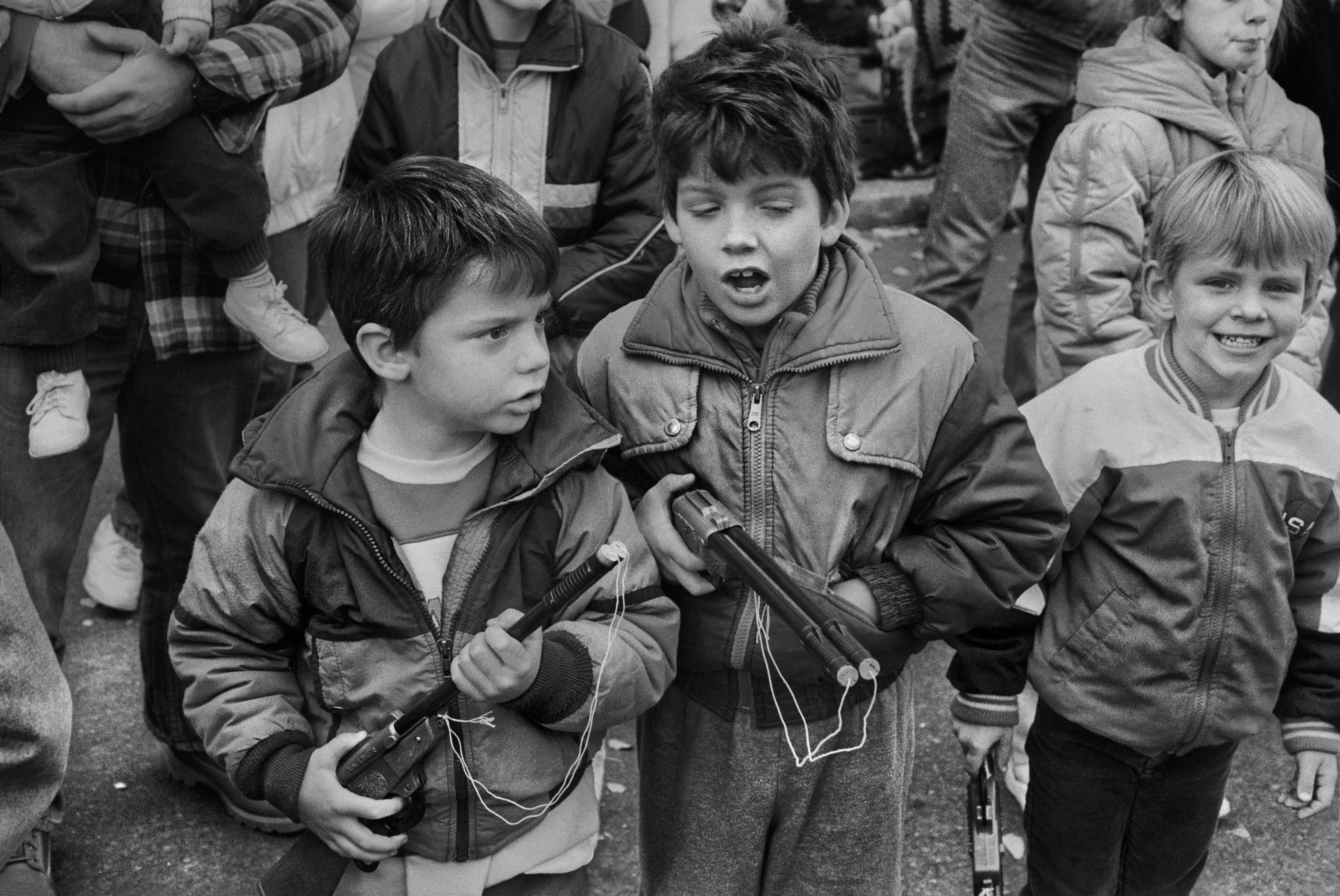 Black and white photo of children playing with toy guns outdoors, captured candidly.