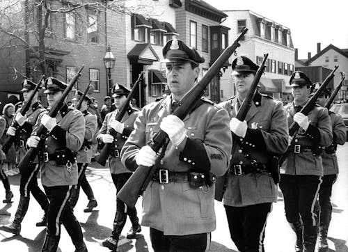 A Grayscale of Soldiers Holding Rifles