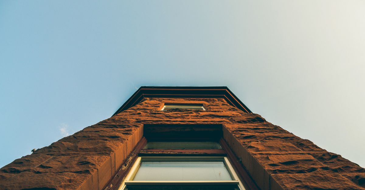 Low angle shot of a brick building's facade reaching towards the clear blue sky.