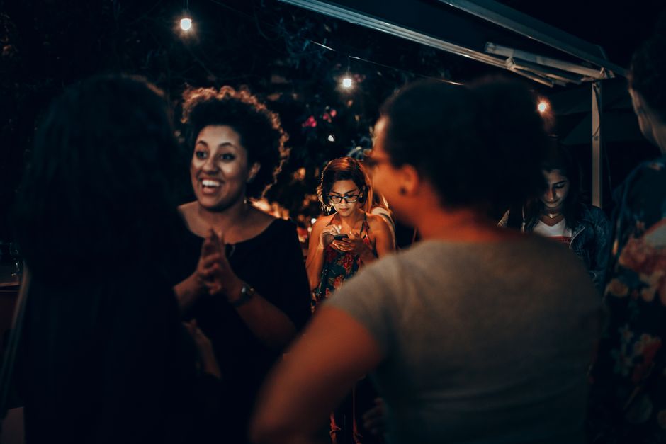 A cheerful group of friends enjoying a night party with warm lights.