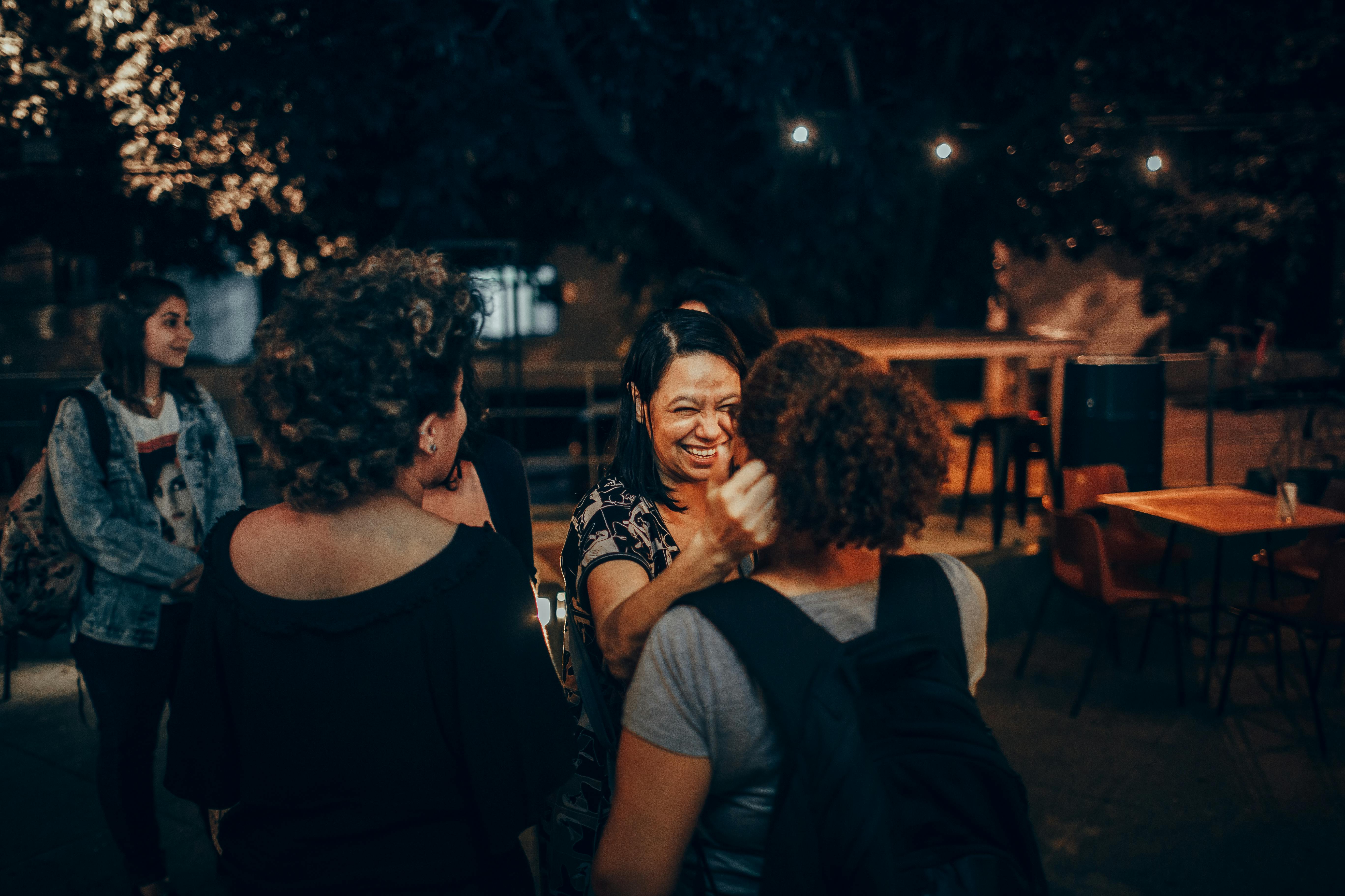 Joyful Evening Gathering in Outdoor Cafe Setting · Free Stock Photo