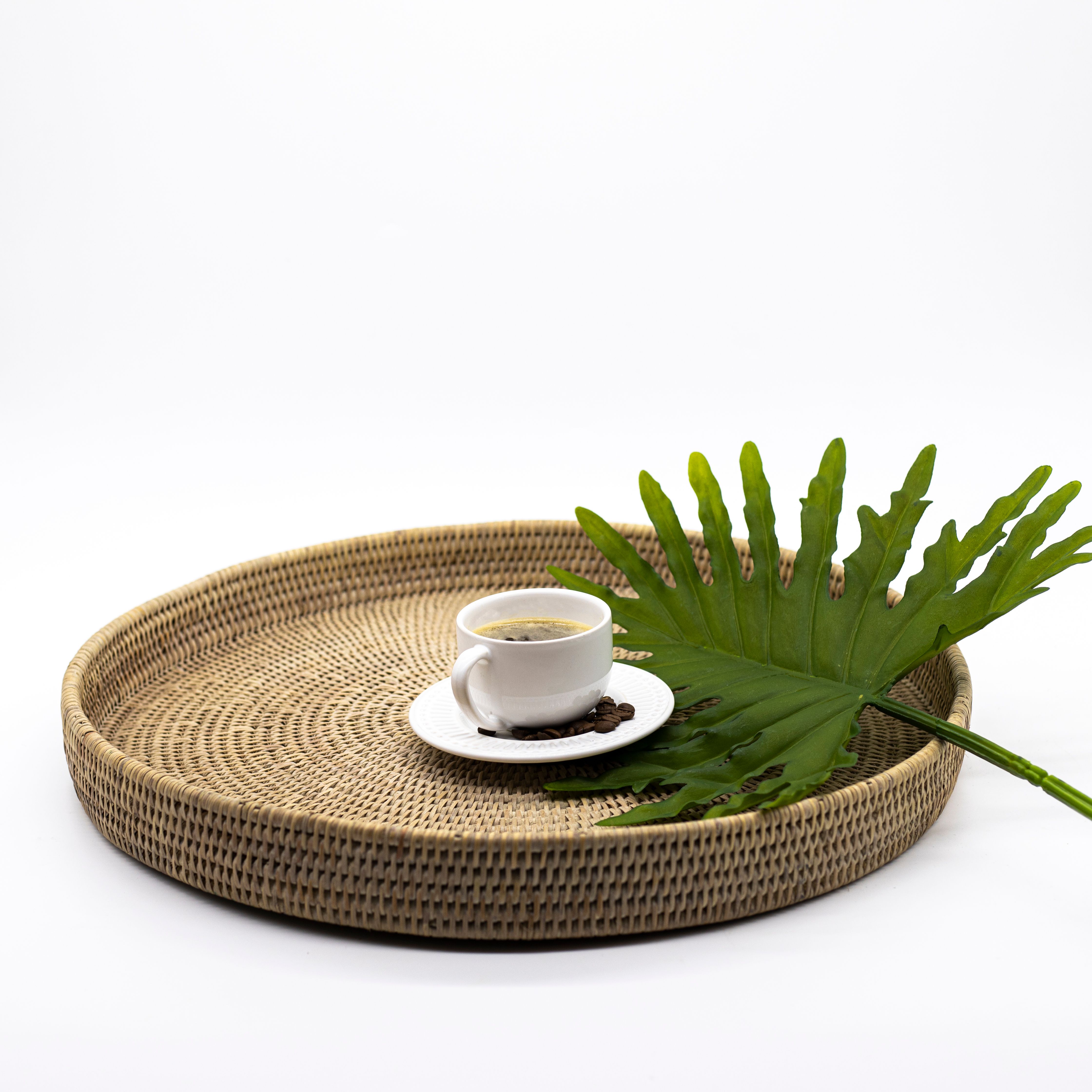 White Ceramic Cup on Brown Woven Round Tray with Green Leaf