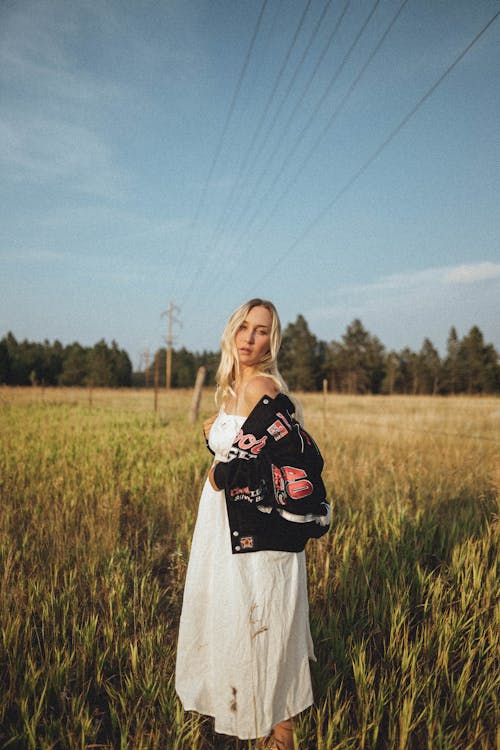 Woman in White Dress Standing on Green Grass Field