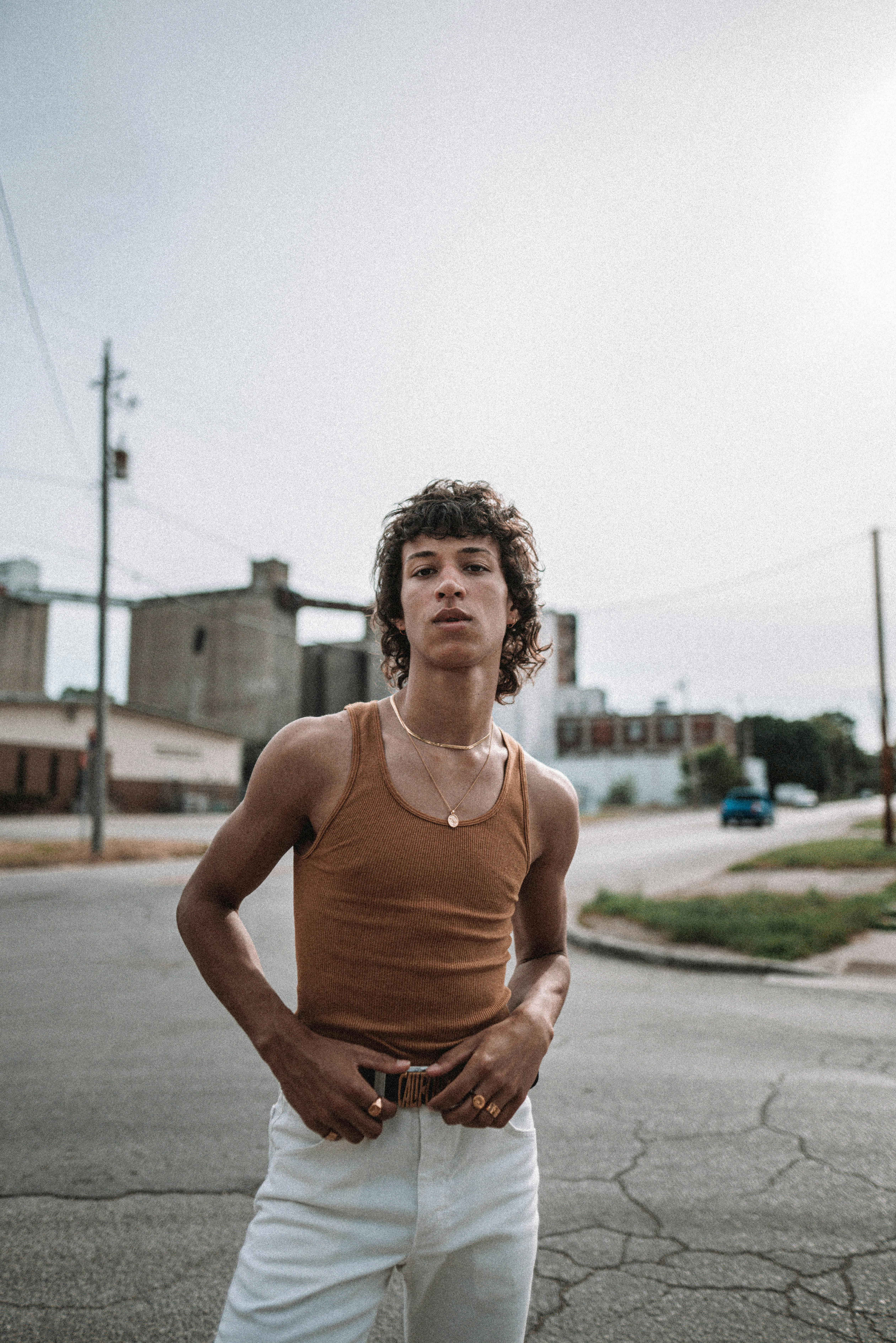 Confident young man in a tank top posing in urban area on a bright day.