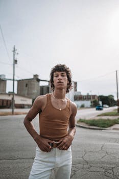 Confident young man in a tank top posing in urban area on a bright day.