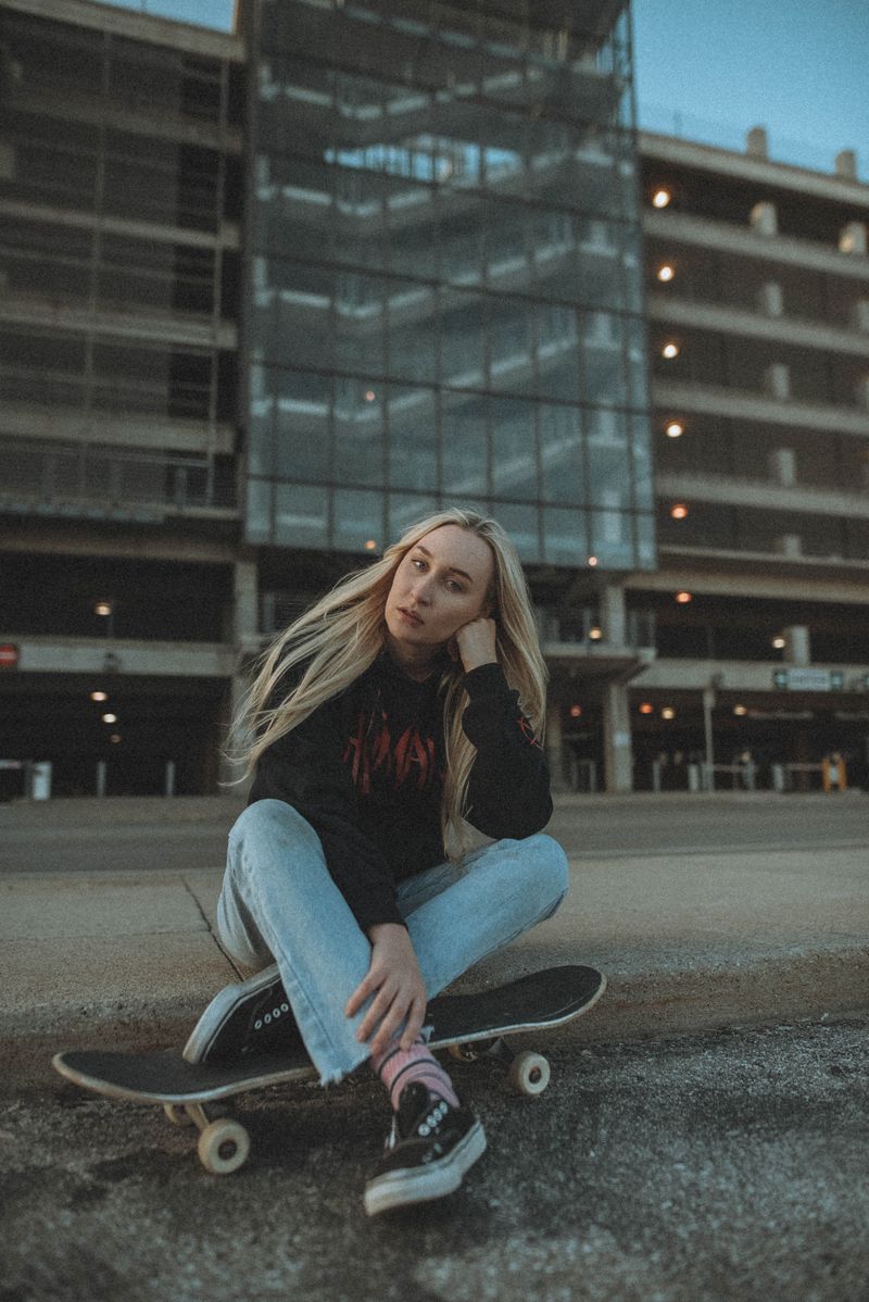 Woman in a black hoodie sitting on a skateboard