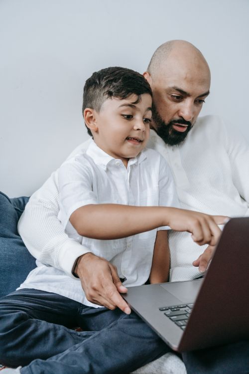 Free A father and son sharing a moment while using a laptop together. Stock Photo