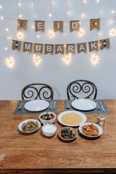 Festive Eid Mubarak dinner setup with diverse dishes on a wooden table, ready for celebration.