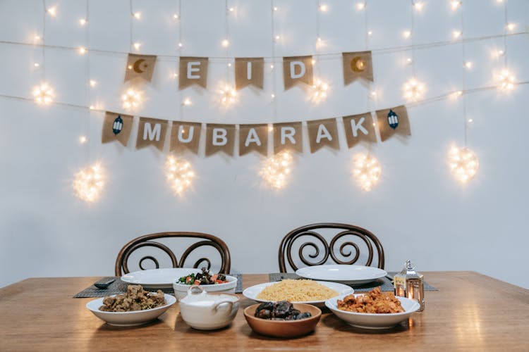 Table With Food And A Decoration On The Wall Saying Eid Mubarak 