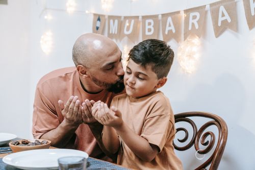 Free A touching father-son moment during a festive occasion with warm lighting and decoration. Stock Photo