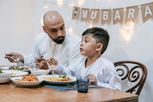 Free Father and son enjoy a festive meal during Eid Mubarak celebration. Stock Photo