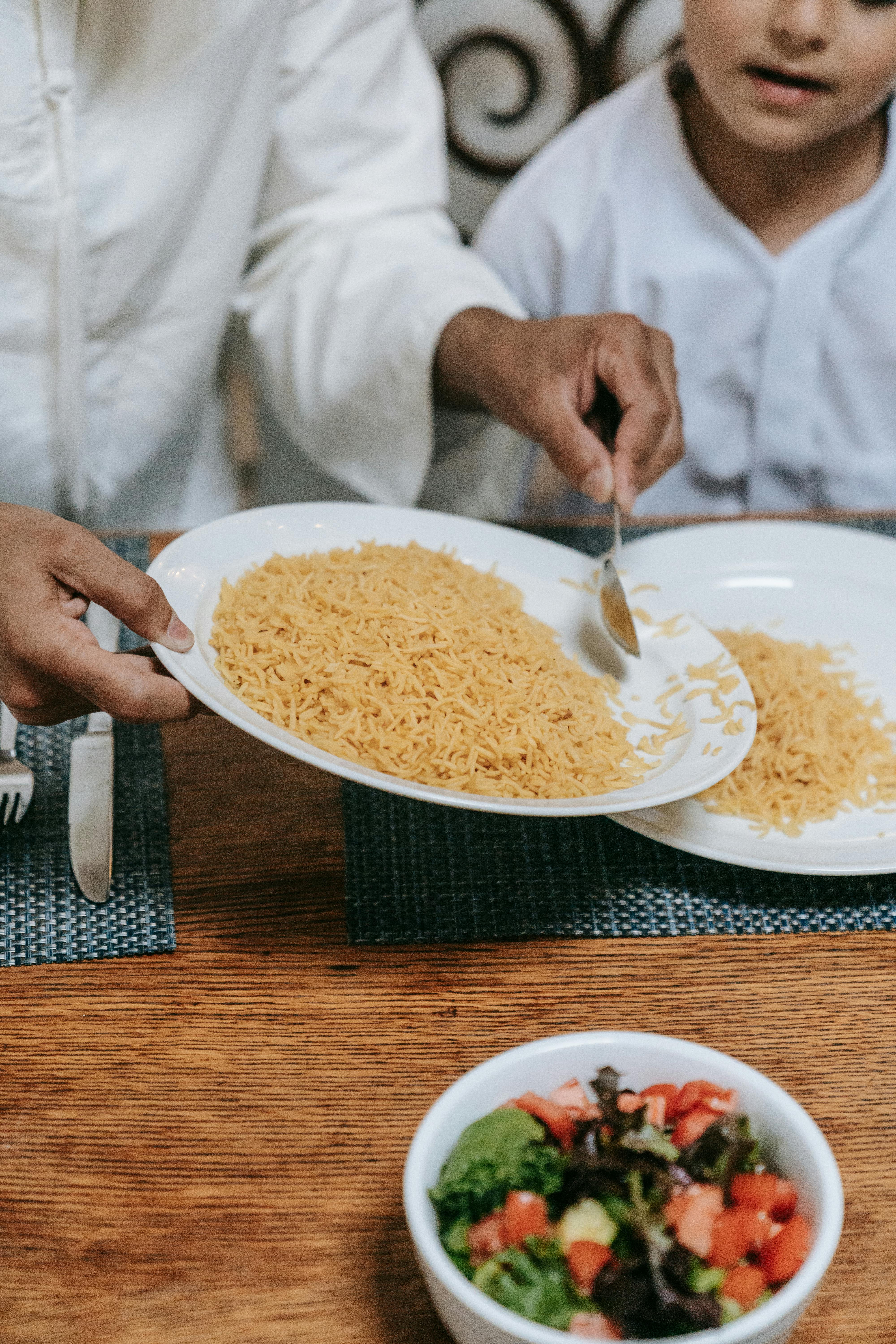 Close-up of rice being served with a fresh salad on a wooden table.