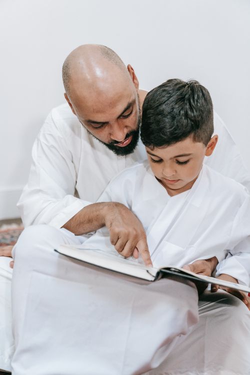 Free Father reading with his son in traditional clothing, fostering energy and togetherness. Stock Photo