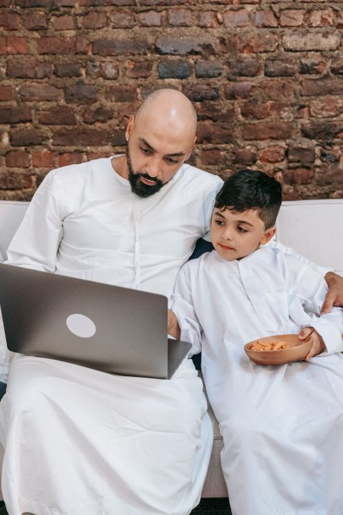 Free Middle Eastern father and son spending quality time on the laptop indoors. Stock Photo