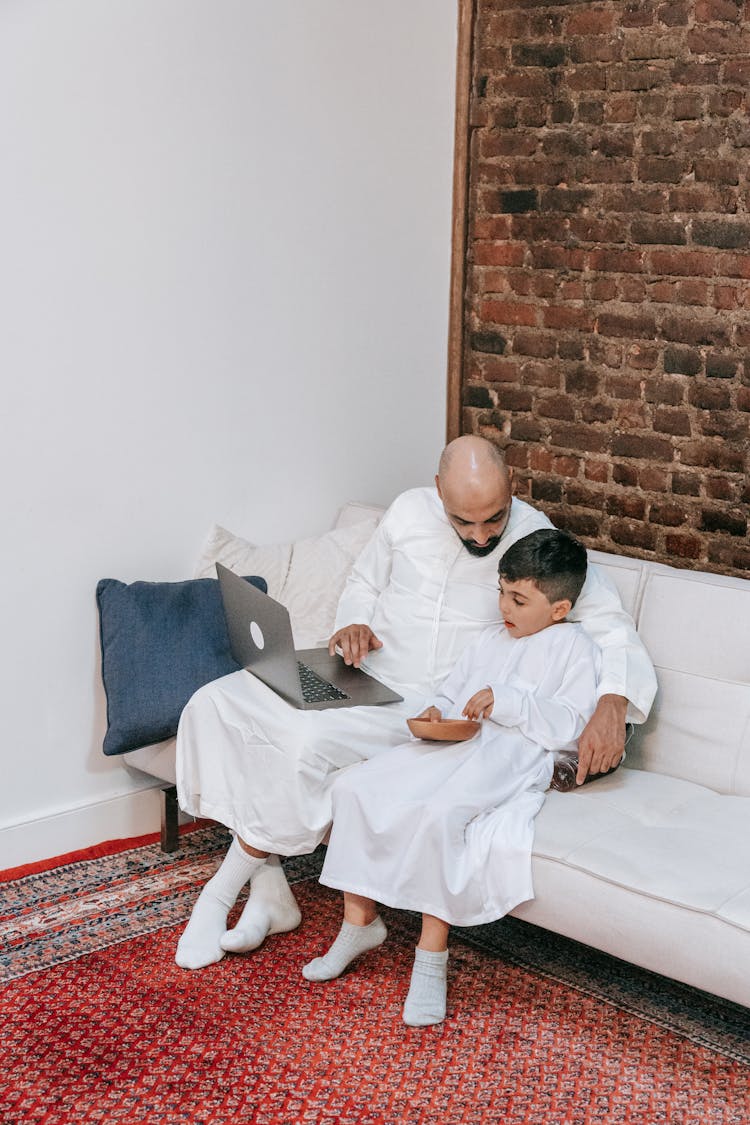 Father And Son Sitting Together On A Sofa