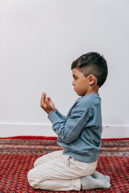 Free Boy in Blue Sweater Sitting on Floor Extending His Arm  Stock Photo