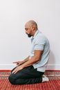 Bald Man in Blue Polo Shirt and Black Pants Kneeling on Carpet