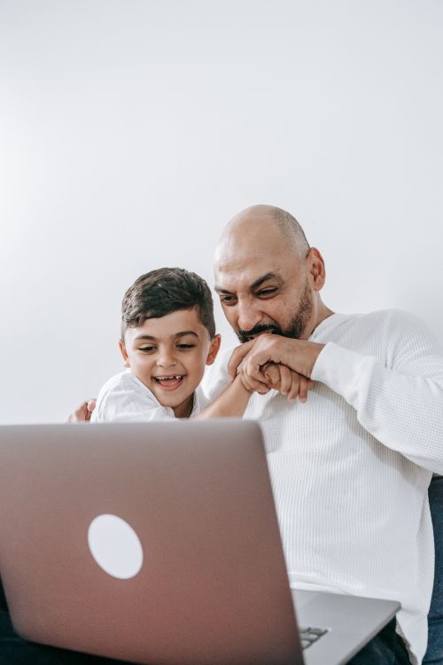 Free A father and son enjoying quality time together, watching a laptop indoors. Stock Photo