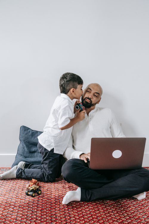 Free Parent and child bonding over a kiss while using a laptop on the floor. Stock Photo
