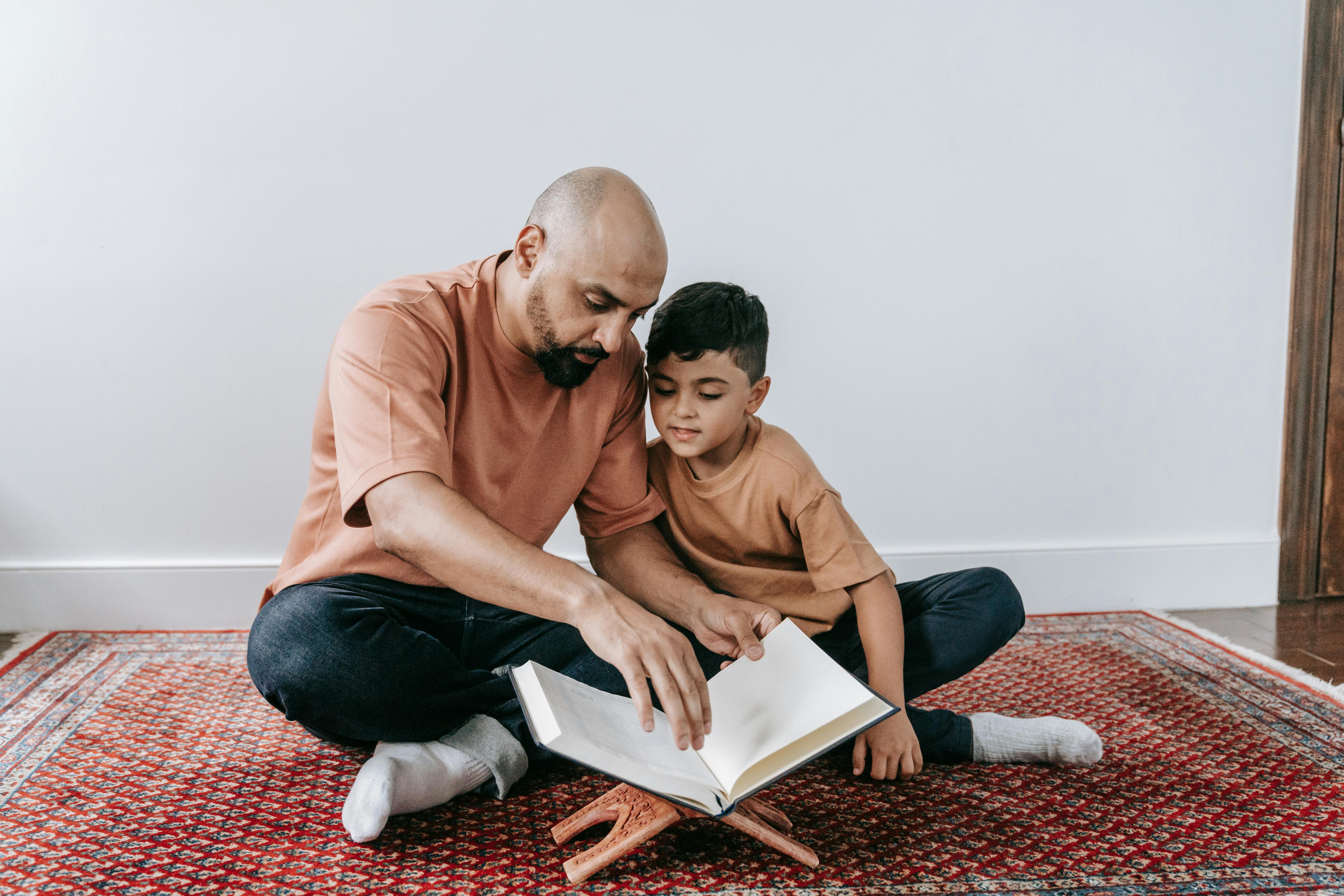 A father and son sitting on a rug, bonding over reading indoors.