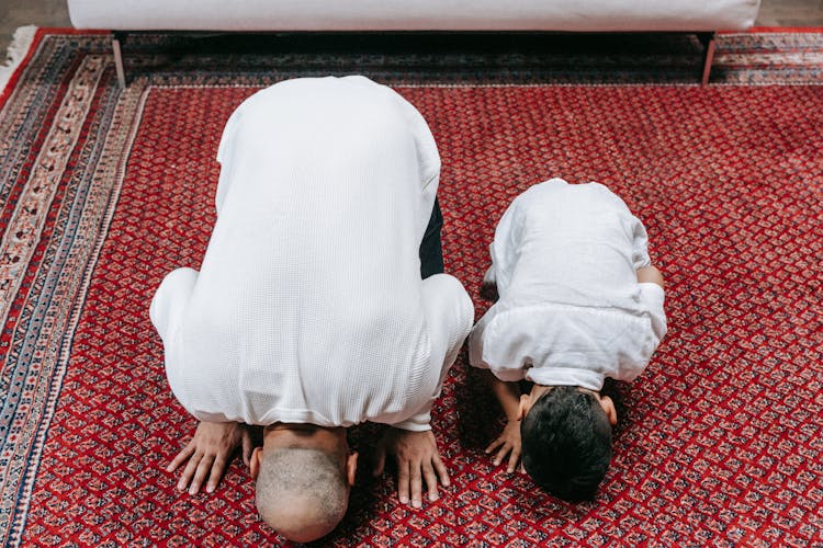 A Man And A Boy Kneeling On Floor Bowing